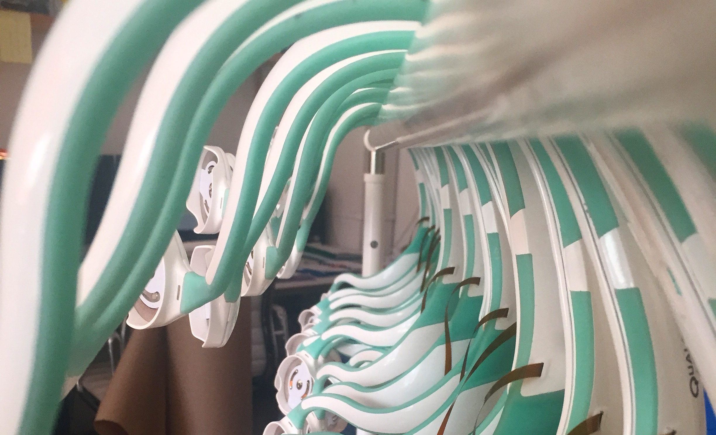 Row of identical curved plastic device housings with integrated flex circuits staged on a rack—illustrating DFM focus on repeatability, alignment, and scalable assembly