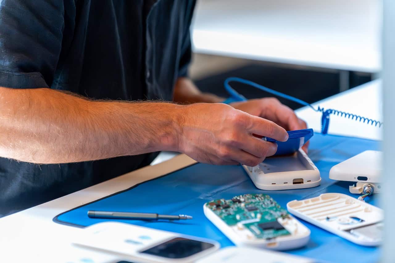 Design for Manufacturing (DFM) in practice: technician assembling device with accessible PCB test pads and a programming port for pre-assembly verification